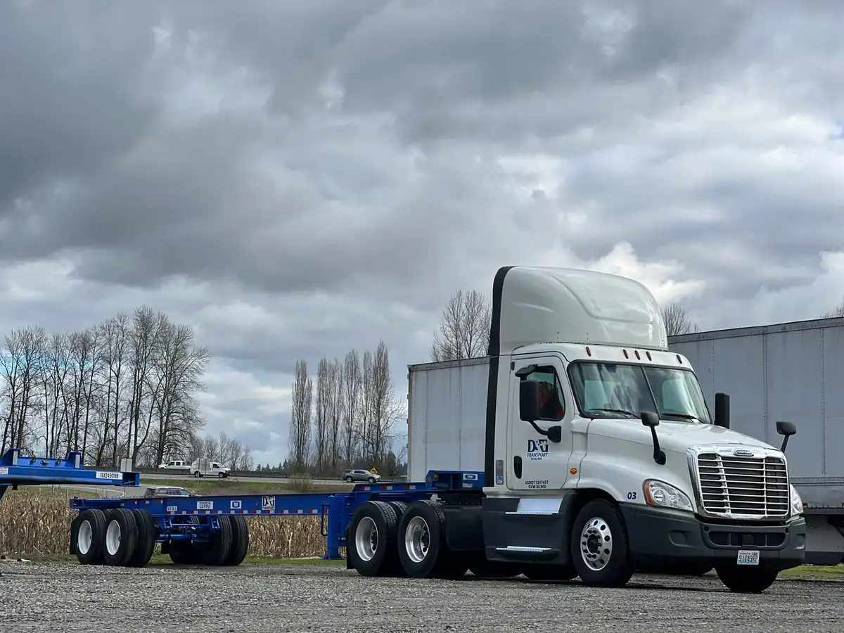 D&G Transport day cab beside a blue extendable container chassis along the I-5 corridor